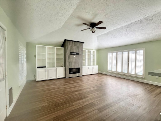 unfurnished living room with lofted ceiling, ceiling fan, a fireplace, a textured ceiling, and wood-type flooring