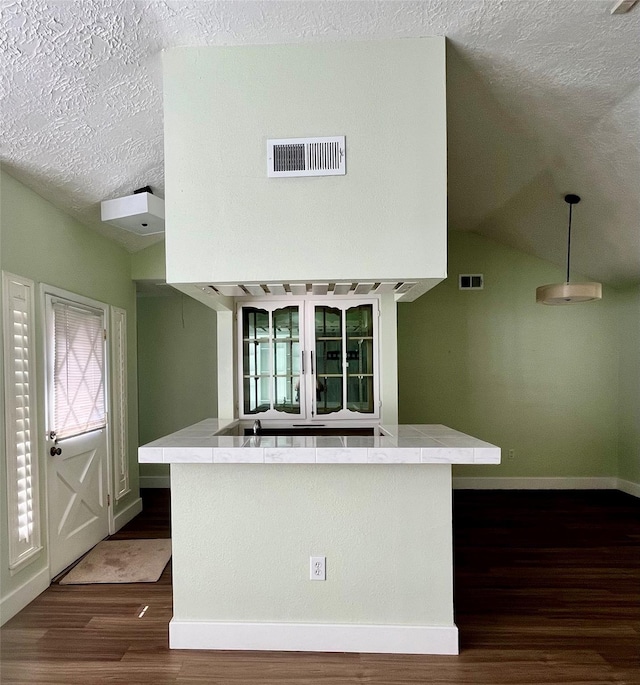 kitchen with a textured ceiling, lofted ceiling, dark hardwood / wood-style flooring, and decorative light fixtures