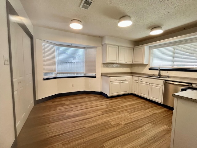 kitchen with dishwasher, white cabinets, sink, a textured ceiling, and light hardwood / wood-style floors