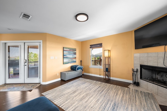 living room featuring a tile fireplace, french doors, dark hardwood / wood-style floors, and a healthy amount of sunlight