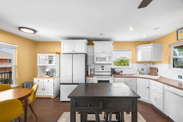 kitchen with tasteful backsplash, white appliances, sink, white cabinets, and a kitchen island