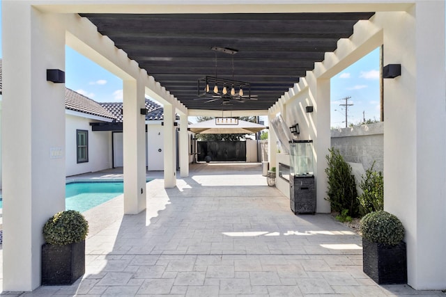 view of patio / terrace featuring a gazebo, ceiling fan, a fenced in pool, and an outdoor kitchen