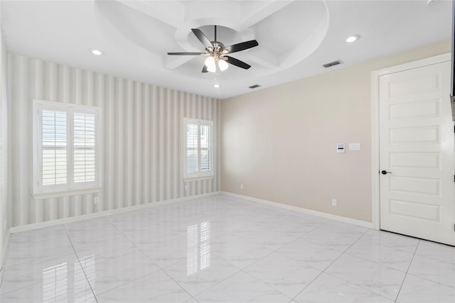 spare room featuring ceiling fan and a raised ceiling