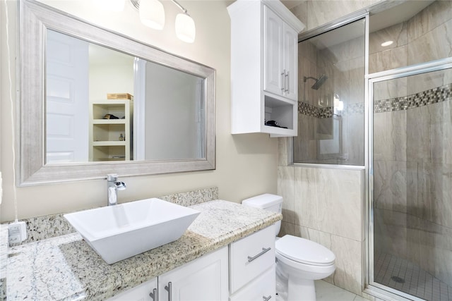 bathroom with a shower with door, vanity, and toilet