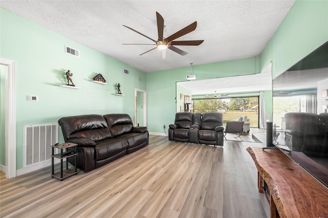 living room featuring ceiling fan, a textured ceiling, and light hardwood / wood-style flooring