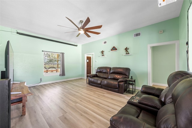 living room with ceiling fan, light hardwood / wood-style floors, and a textured ceiling