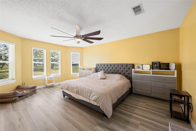 bedroom featuring ceiling fan, wood-type flooring, and a textured ceiling