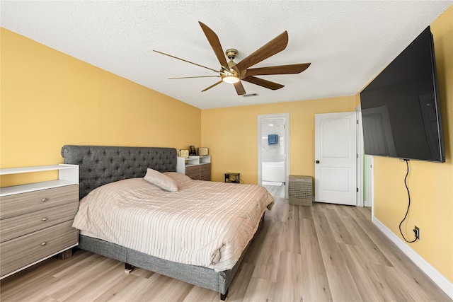 bedroom with a textured ceiling, ceiling fan, ensuite bathroom, and light hardwood / wood-style flooring