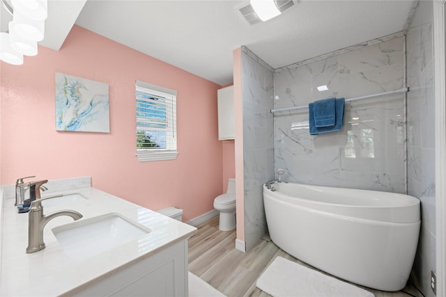 bathroom with hardwood / wood-style floors, vanity, a washtub, toilet, and a textured ceiling