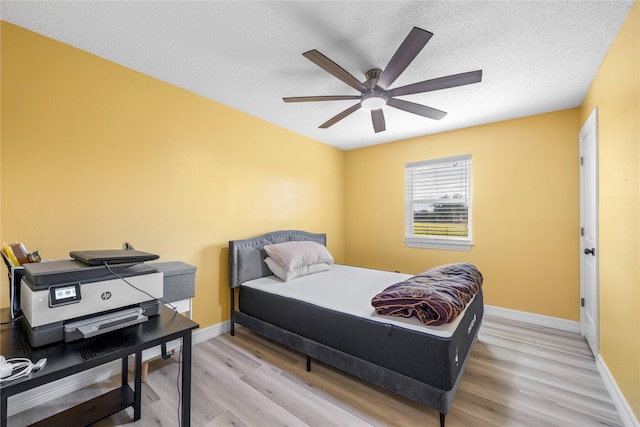 bedroom featuring ceiling fan, light wood-type flooring, and a textured ceiling