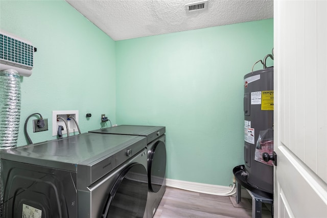 laundry room featuring light wood-type flooring, a textured ceiling, electric water heater, and washing machine and clothes dryer