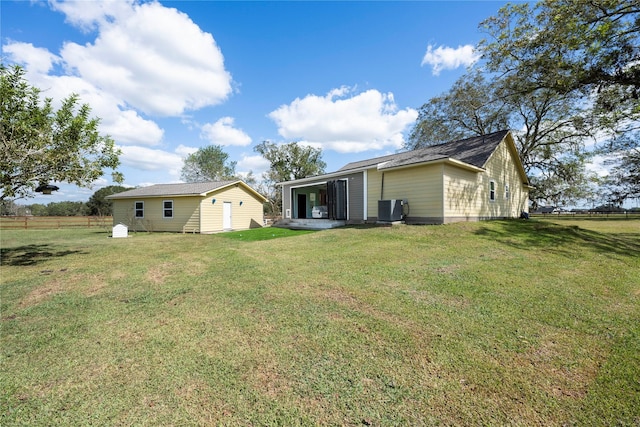 back of property featuring a lawn, cooling unit, and an outbuilding