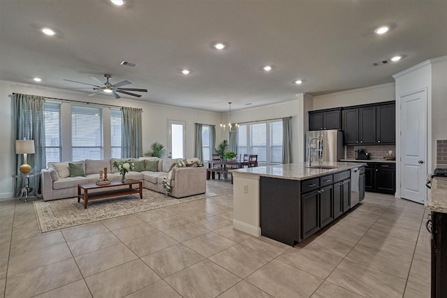 kitchen featuring ceiling fan with notable chandelier, sink, an island with sink, light stone counters, and stainless steel fridge with ice dispenser