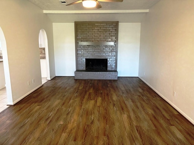 unfurnished living room with beamed ceiling, dark hardwood / wood-style flooring, and a brick fireplace