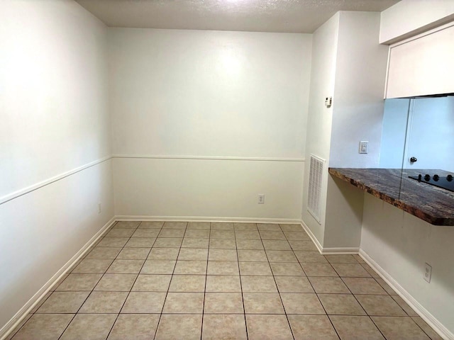 tiled spare room featuring a textured ceiling