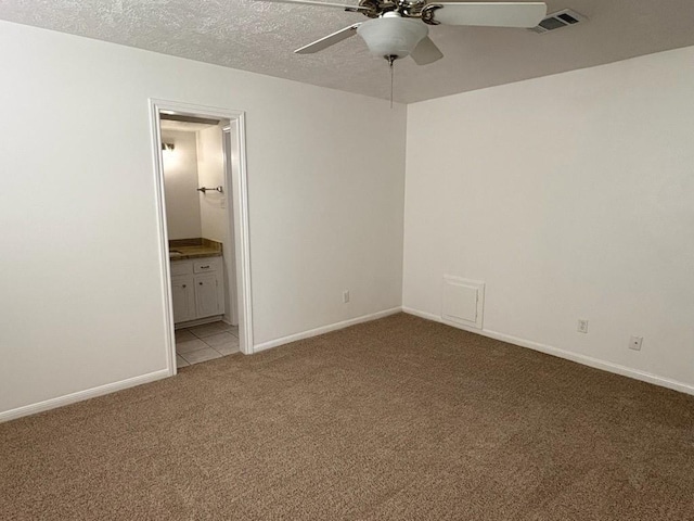 empty room featuring ceiling fan, light colored carpet, and a textured ceiling