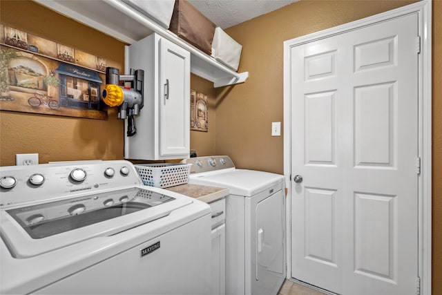 laundry room with washing machine and clothes dryer, cabinets, and a textured ceiling