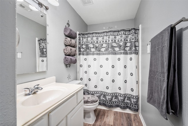 bathroom with a shower with curtain, vanity, wood-type flooring, and toilet