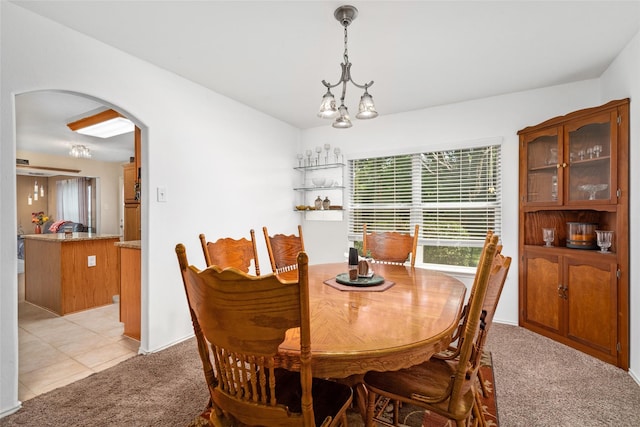 carpeted dining area with an inviting chandelier