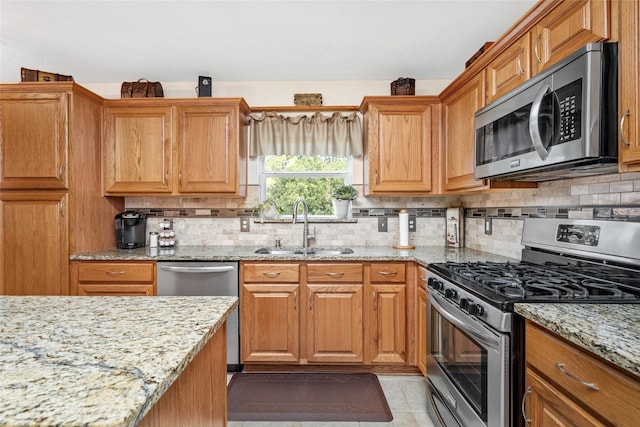 kitchen featuring backsplash, stainless steel appliances, light stone counters, and sink