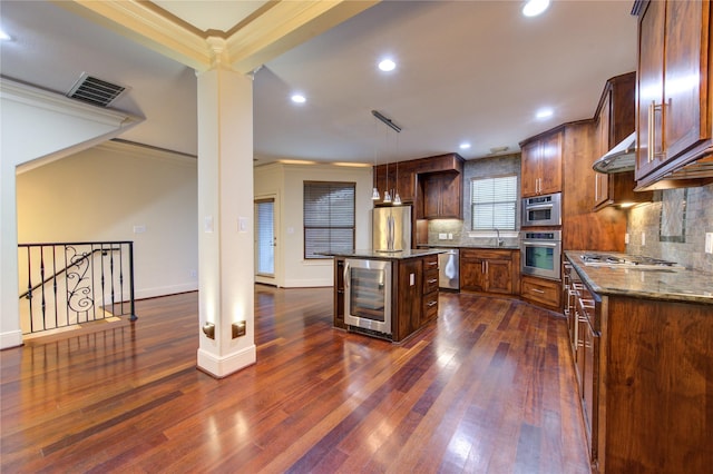 kitchen with a center island, wine cooler, crown molding, pendant lighting, and appliances with stainless steel finishes