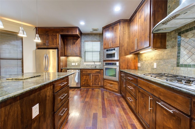 kitchen with ventilation hood, stainless steel appliances, dark stone counters, and tasteful backsplash