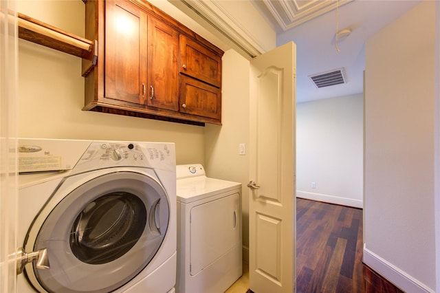 laundry area featuring dark hardwood / wood-style flooring, cabinets, and washing machine and clothes dryer