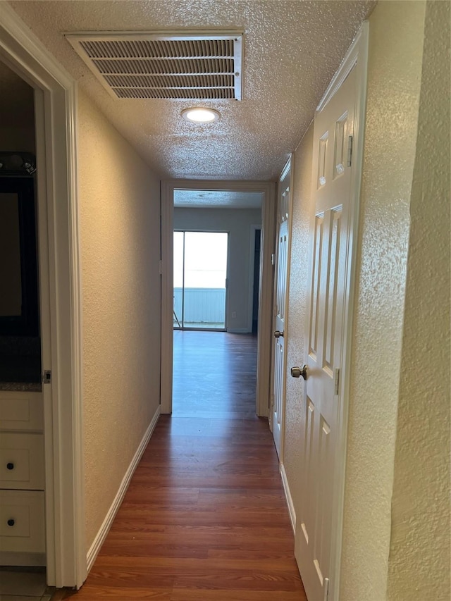 hallway with hardwood / wood-style floors and a textured ceiling