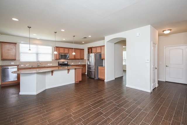 kitchen with a center island, backsplash, sink, hanging light fixtures, and appliances with stainless steel finishes