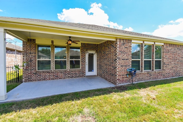 view of exterior entry with a lawn, ceiling fan, and a patio area