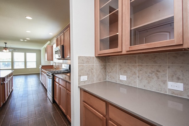 kitchen featuring backsplash, ceiling fan, dark wood-type flooring, and stainless steel appliances