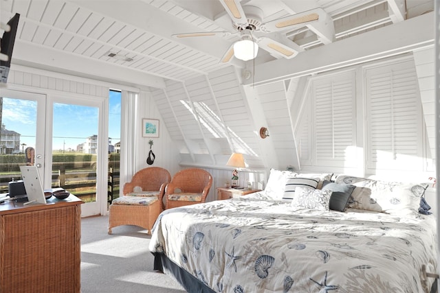 carpeted bedroom featuring lofted ceiling, access to exterior, ceiling fan, and wood walls