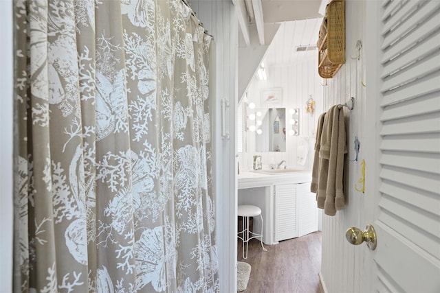 bathroom with hardwood / wood-style floors, vanity, a shower with curtain, and wooden walls