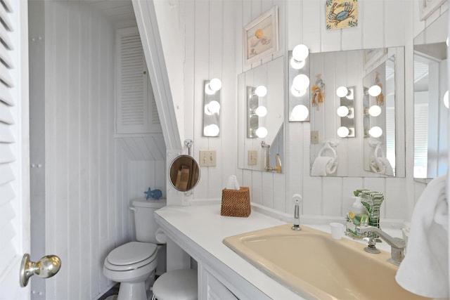 bathroom featuring wood walls, vanity, and toilet