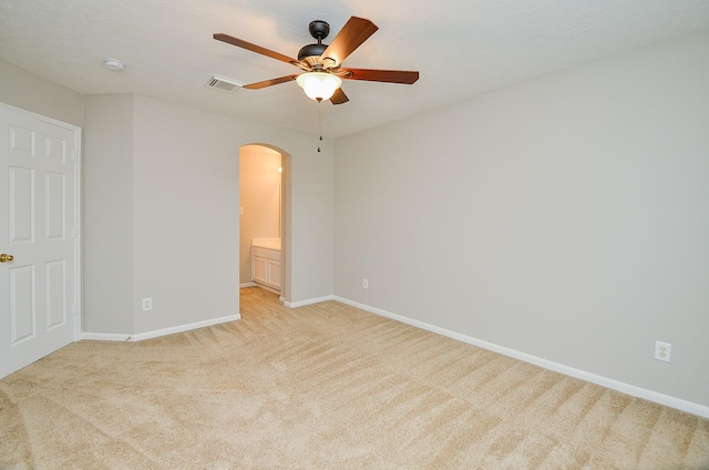 unfurnished bedroom with light carpet, connected bathroom, and ceiling fan