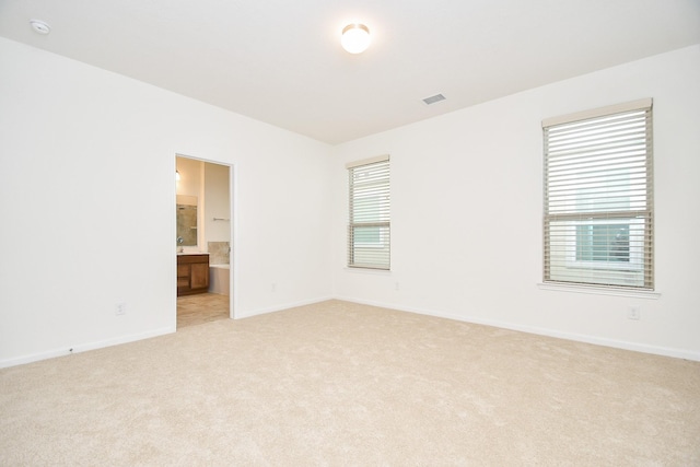 unfurnished room featuring baseboards, visible vents, and light colored carpet