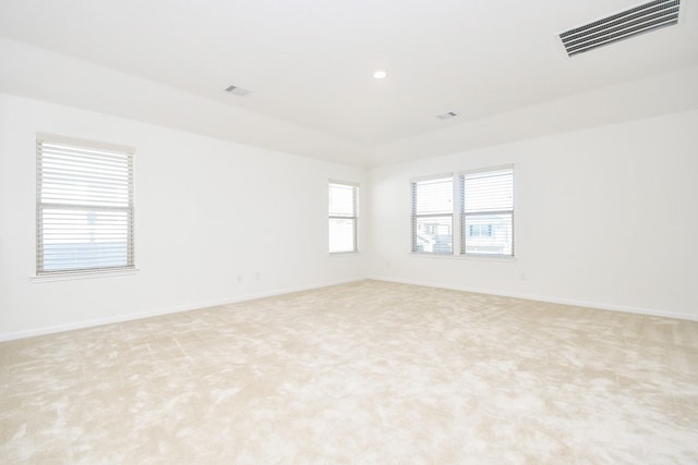 empty room with light colored carpet, visible vents, and baseboards