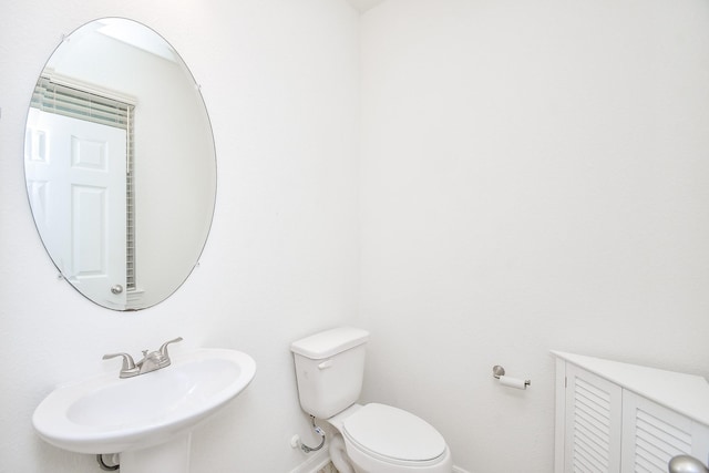 bathroom with a sink, toilet, and baseboards