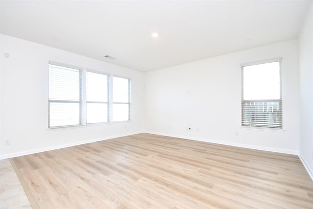 empty room featuring baseboards, visible vents, a wealth of natural light, and light wood-style floors