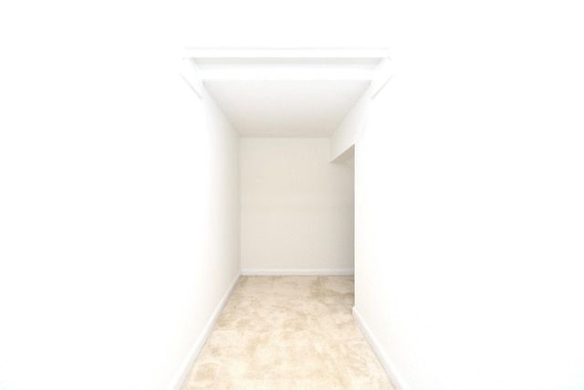 spare room featuring light carpet and baseboards