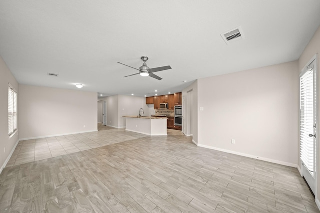 unfurnished living room with light wood-type flooring, sink, and ceiling fan