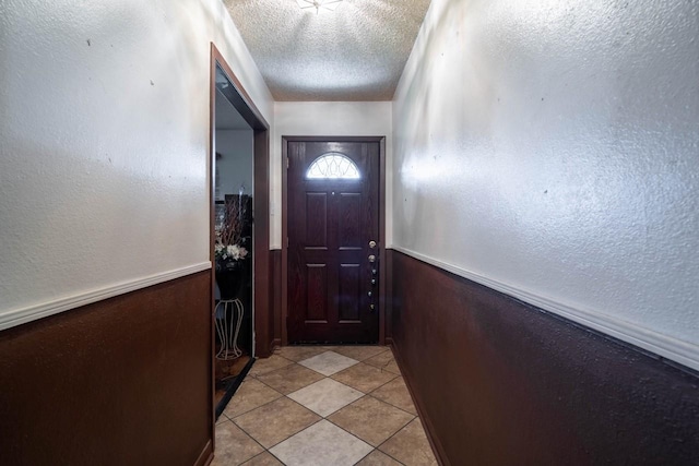 doorway featuring light tile patterned flooring and a textured ceiling