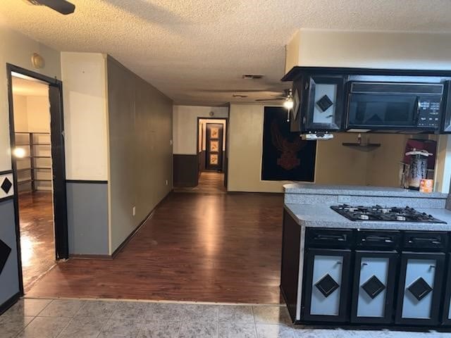 kitchen featuring tile patterned flooring, a textured ceiling, and stainless steel gas cooktop