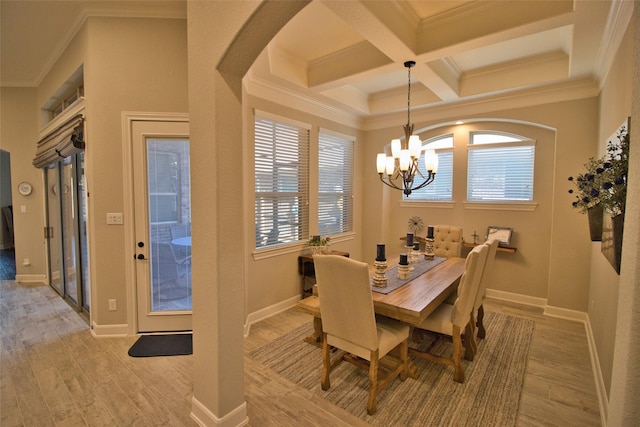 dining room with light wood-type flooring, ornamental molding, a healthy amount of sunlight, coffered ceiling, and a chandelier