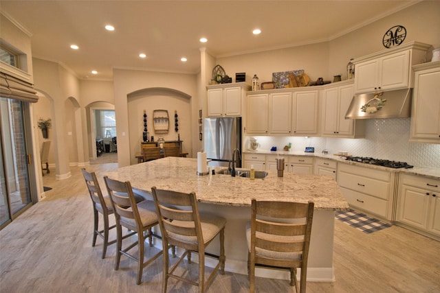 kitchen with light stone counters, stainless steel appliances, a spacious island, a kitchen breakfast bar, and sink