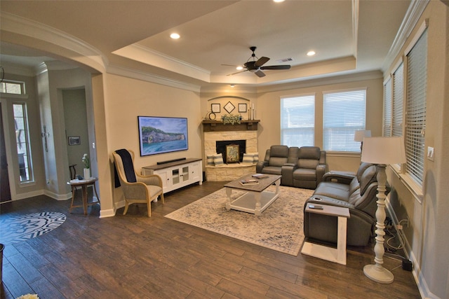 living room featuring ceiling fan, dark wood-type flooring, a fireplace, and a tray ceiling