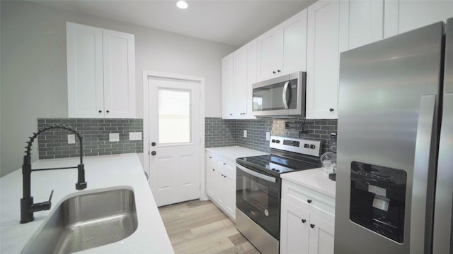 kitchen featuring white cabinets, decorative backsplash, sink, and appliances with stainless steel finishes