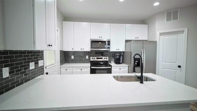 kitchen featuring white cabinets, appliances with stainless steel finishes, tasteful backsplash, and sink