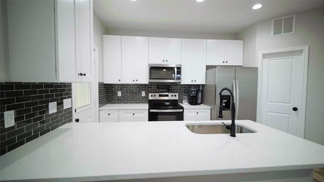 kitchen featuring white cabinets, sink, stainless steel appliances, and tasteful backsplash