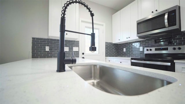 kitchen featuring light stone counters, white cabinetry, stainless steel appliances, and tasteful backsplash